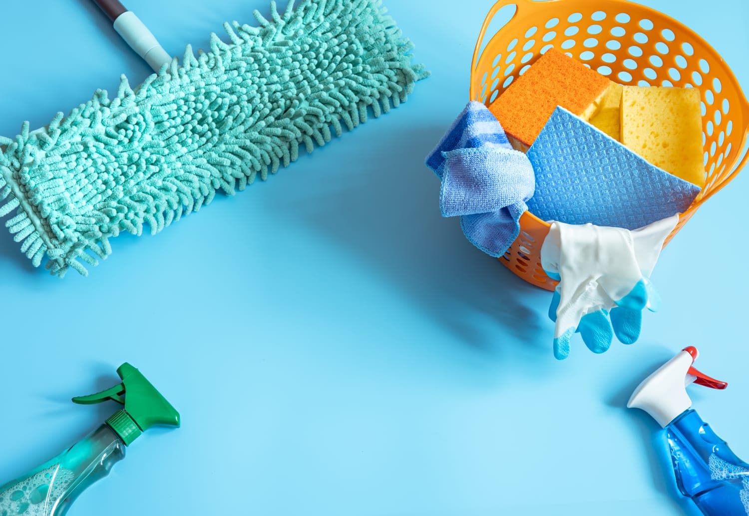 Professional cleaning supplies laid out flat — microfibre mop head, sponges, cloths, gloves and spray bottles