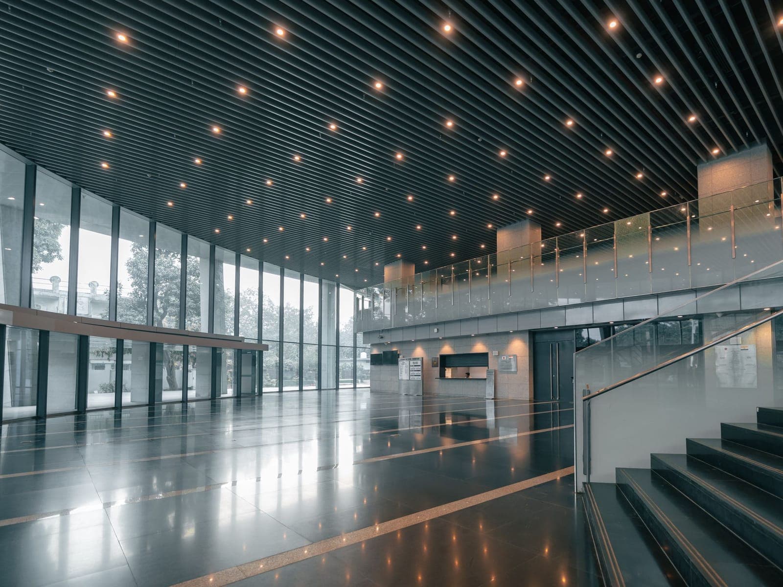 The atrium of a modern commercial building with a polished stone floor, glass curtain wall and reception desk