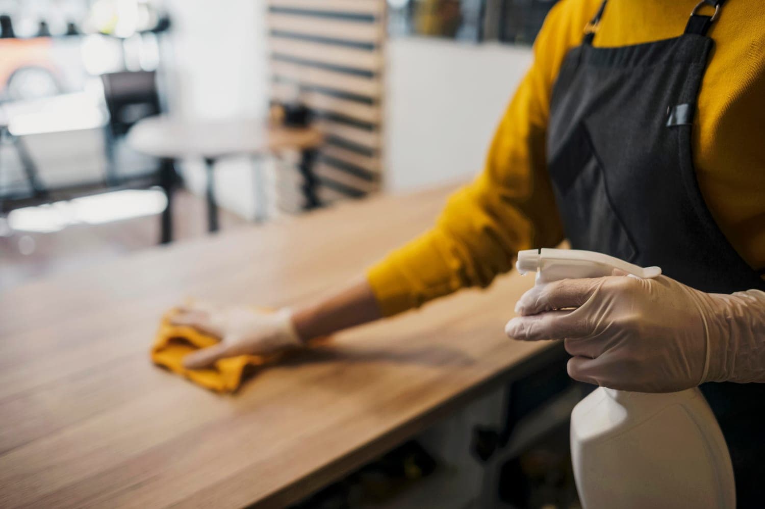 A gloved technician spraying and wiping a counter surface during a service visit